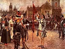 Kościuszko portant une veste rayée tient un sabre à l'horizontal et lève deux doigts pour prêter serment devant plusieurs dignitaires en costume de cérémonie. Des soldats en uniforme se tiennent à l'arrière-plan devant des bâtiments de style néoclassique.