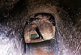 Photographie en couleurs d'une nappe d'eau au bas d'un escalier taillé dans la pierre.