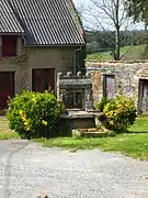 Photographie en couleurs d'un puits en pierre dans un hameau.