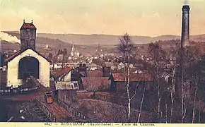 De gauche à droite : La recette du puits surmonté du chevalement en bois, à l'arrière plan, on aperçoit le chevalement en béton du puits sainte-Marie, en dessous de l'église on aperçoit le petit chevalement métallique du puits de secours, la cheminée du ventilateur et la cheminée des chaudières.