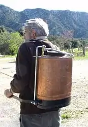 Pulvérisateur traditionnel à dos en cuivre à pression entretenue au moyen du levier à gauche.