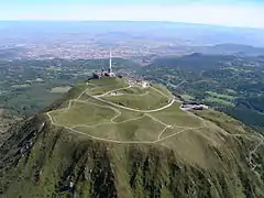 Vue aérienne du puy de Dôme depuis l'ouest avec Clermont-Ferrand au second plan et, à l'horizon, le mont Blanc, distant de 315 km.