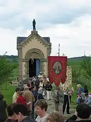 La procession du pèlerinage de sainte Menne à Puzieux devant la chapelle de la sainte.