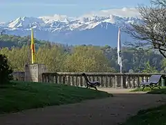 Photo d'un paysage montrant au premier plan un jardin public et au fond des montagnes enneigées.