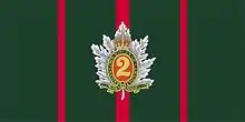 Un drapeau vert forêt avec trois bandes verticales minces rouges, celle du centre un peu plus large que les deux autres, et un insigne militaire au centre