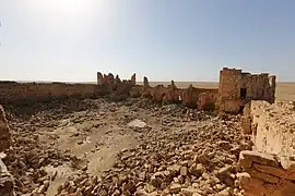 Cour couverte de moellons entourée de murs en ruine