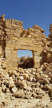 porte dans un mur de pierres blondes en ruine