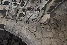 partie d'arche sous un plafond de poutres en pierre