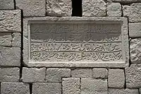 inscription de quatre lignes sur une pierre grise rectangulaire