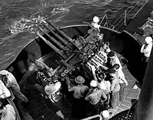Photographie en plongée d'un affût quadruple autour duquel s'affairent plusieurs marins.