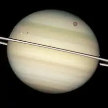 Vue au niveau des anneaux montrant différentes sphères blanches ou rouges devant Saturne.