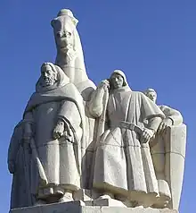 Photographie d'un monument en granit représentant quatre chevaliers à pied autour d'un cheval. Ce monument est érigé en hauteur au sommet d'une colline de la vallée de la Meuse en Ardennes