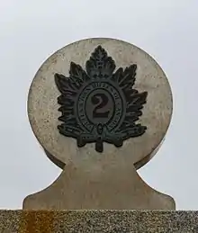 Détails d'un monument montrant un insigne militaire sur une forme de ciment arrondie