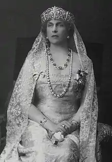 Portrait de trois-quarts d'une femme assise portant un diadème, un voile et un long collier de perles.