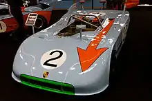 Un spider Porsche 908/3 de 1971 en livrée bleu ciel et orange.