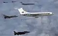 Photographie de de deux VC10 en vol, entourés de quatre avions de combat, dont un sur le point de s'accrocher à un panier de ravitaillement.