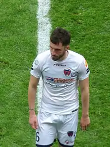 Photographie d'un joueur de football avec un maillot blanc regardant devant lui.