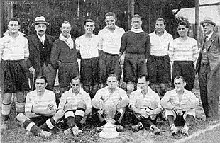 Photo d'équipe sur deux rangs, dont l'un où les joueurs sont assis. Une coupe est posée devant le premier rang.