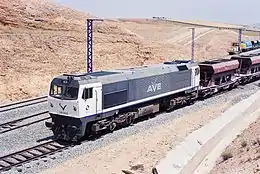 la photo couleur montre une locomotive bleu foncé à cabines blanches sur un train de ballast.