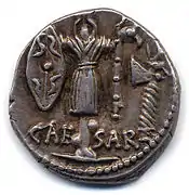 Revers d'une monnaie de Jules César figurant un trophée avec bouclier gaulois, carnyx ; sur la droite une hache (Crawford, Roman Republican Coinage, 452/2).