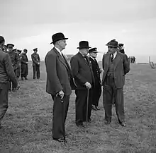 Photographie en noir et blanc d'un groupe d'hommes debout et en discussion.