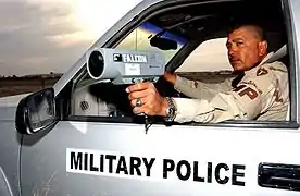 Un policier militaire utilisant un pistolet radar pour mesurer la vitesse des automobiles à la base aérienne de Tallil, Irak.