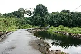 Vue de l'Îlet Coco depuis un radier sur la Rivière des Marsouins qui y donne accès.