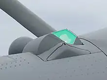 Vue en gros plan de profil du capteur TV/IR de l'OSF, protégé par un hublot aérodynamique qui apparait vert. La carlingue de l'avion est grise.