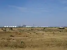 Photographie d'une raffinerie sur fond de paysage sahélien.