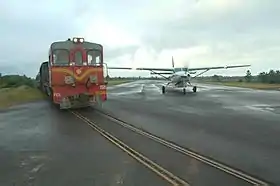 Vue d'un train passant devant un avion sur une piste.
