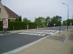 Un ralentisseur avec la signalisation adéquate (noter les largeurs différentes de part et d'autre)