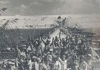 Photographie montrant au premier plan des soldats égyptiens posant devant un des ponts construits sur le canal de Suez