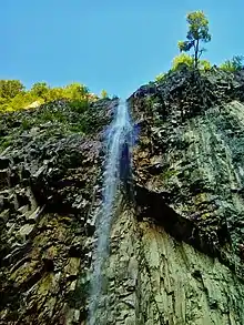 Un ruisseau s'écroule dans le vide le long d'une paroi verticale de roches.