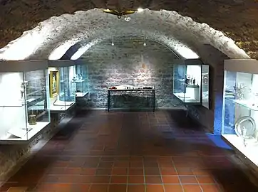 Vue d’une salle d’exposition : cave médiévale avec voûte.