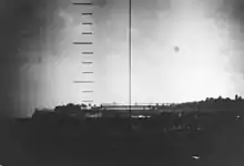 Photo en noir et blanc montrant des bâtiments peu élevés au bord de la mer.