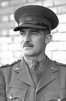 Portrait tête et épaules d'un homme moustachu en uniforme militaire avec une casquette à visière.