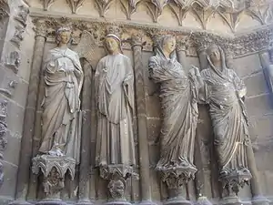 Quatre statues contre des colonnes encastrées : l'ange regarde la Vierge, une seconde Vierge est tournée vers Élizabeth.