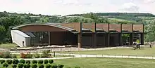 Vue d'un grand bâtiment en bois, verre et pierre abritant un musée.