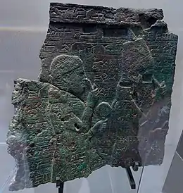Plaque en bronze portant une représentation de la reine mère Naqi'a/Zakutu, derrière son fils Assarhaddon. Musée du Louvre.