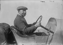 Photo d'un homme, René Thomas, au volant d'une voiture à l'arrêt.