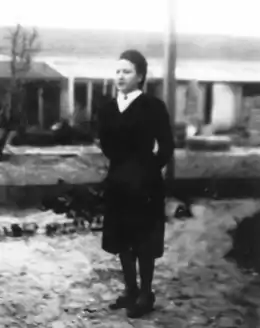 Photo noir et blanc d'une femme debout, de trois quarts face, les mains derrière le dos