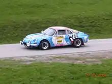 Photo d'une Alpine A110 roulant sur une route de campagne.