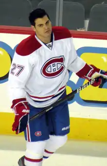 photographie d'un joueur de hockey avec un maillot blanc, sans casque, en train de patiner