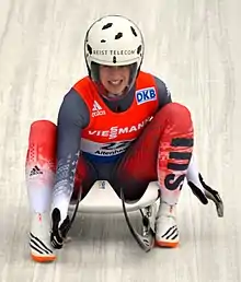 Luuse de face, avec un casque blanc, assise sur sa luge lors de l'arrivée.