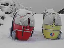 photographie en couleur de deux œufs, l'un rouge, l'autre jaune, posés sur la neige.
