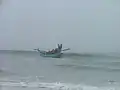 Le bateau revient à la plage après avoir posé le xalavar en mer. On aperçoit derrière le bateau le câble du filet.