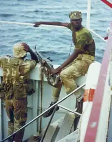 Photographie de deux hommes noirs en uniformes militaires avec un mitrailleuse sur le pont d'un navire