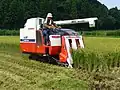 Moissonneuse-batteuse Yanmar sur chenilles au travail dans une rizière asséchée. Japon, 2007.