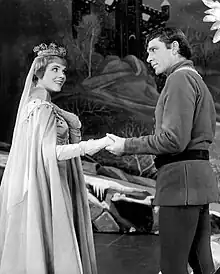 Une femme vêtue en reine (Julie Andrews) tend le bras à un homme (Richard Burton) dans Camelot (1960).