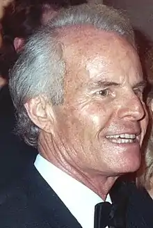 Un homme souriant aux cheveux blancs.